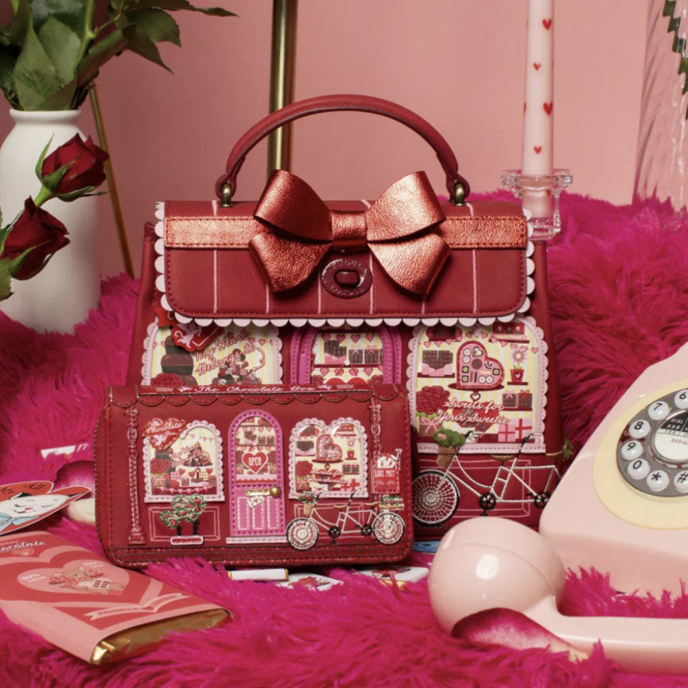 Decorative handbag with heart designs and a large bow on a pink background