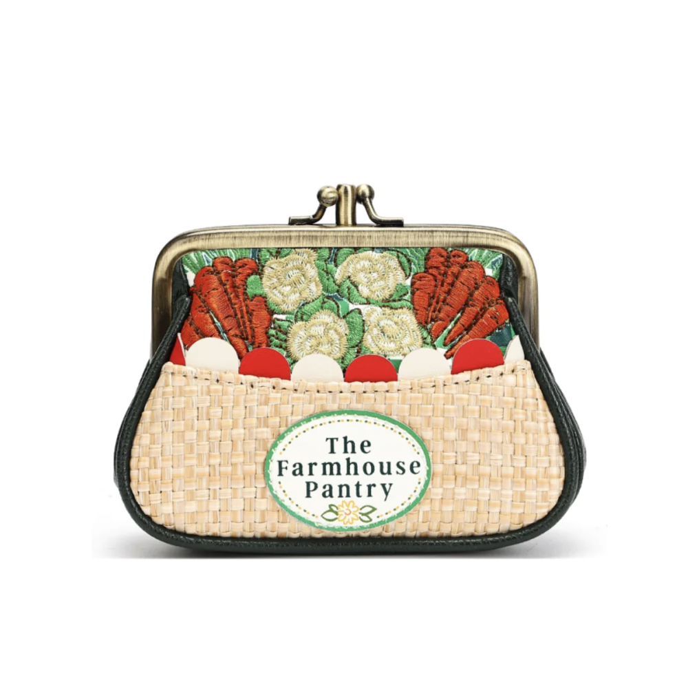 A small kiss-lock purse with a woven straw-like front pocket and a printed vegetable pattern on the flap. The front pocket has a round label reading 'The Farmhouse Pantry'.