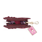 A burgundy zippered coin purse with floral ruffle trim and a pink postage stamp charm attached by a gold-tone chain, shown on a plain white background.