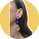Close-up of an ear wearing a colorful earring with a yellow background