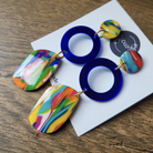 Colorful earrings with blue circular design on a white card