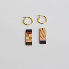 Gold hoop earrings with geometric pendant on a light gray background