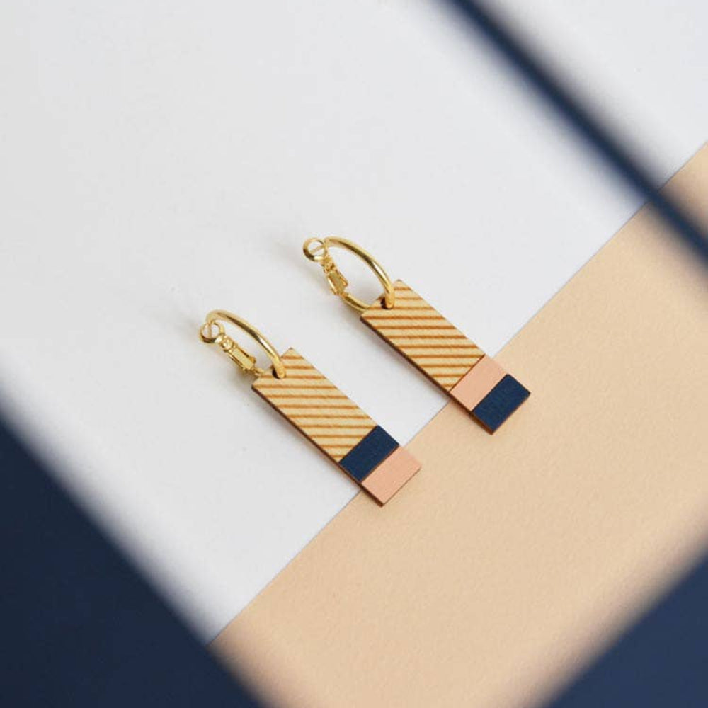 Gold and navy earrings on a light background