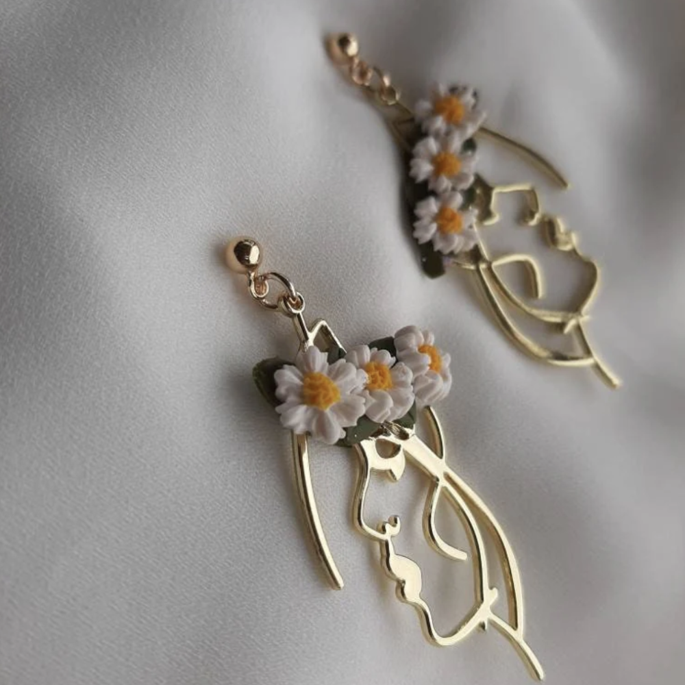 Gold earrings with floral designs on a light gray background