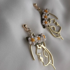 Gold earrings with floral designs on a light gray background