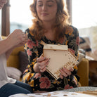 Woman holding a wooden box with 'Bed & Hotel' engraved on it, sitting indoors.