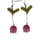 Pair of earrings on a Fionn Herbst branded card with pink charms and green leaves.