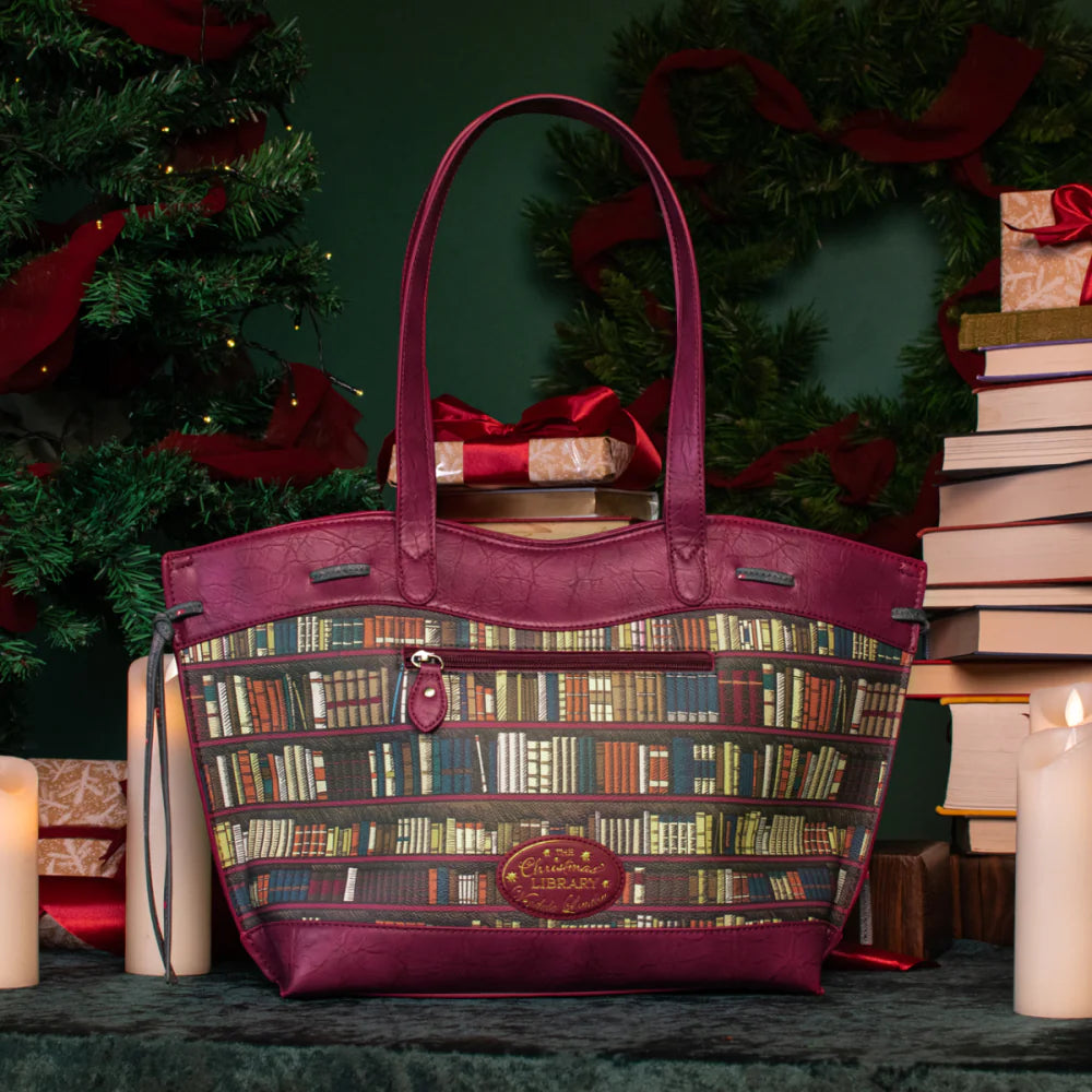 Purple handbag with book pattern in front of a Christmas tree and books