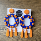 Blue and orange earrings on a display card with 'Duil' branding on a wooden surface.