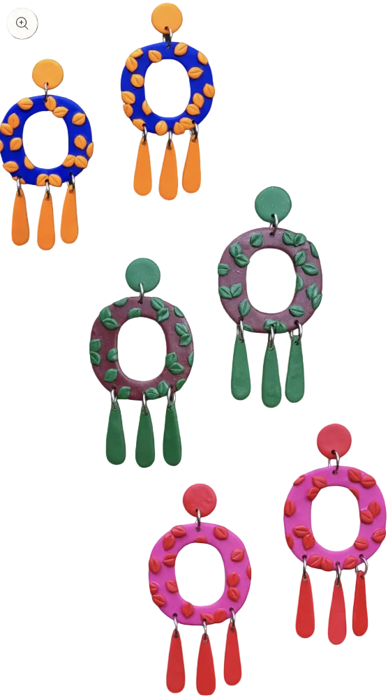 Colorful earrings with circular designs and hanging elements on a dark background