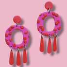 Pink and red earrings on a pink background