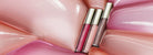 Two lip glosses on a pink and white swirled background