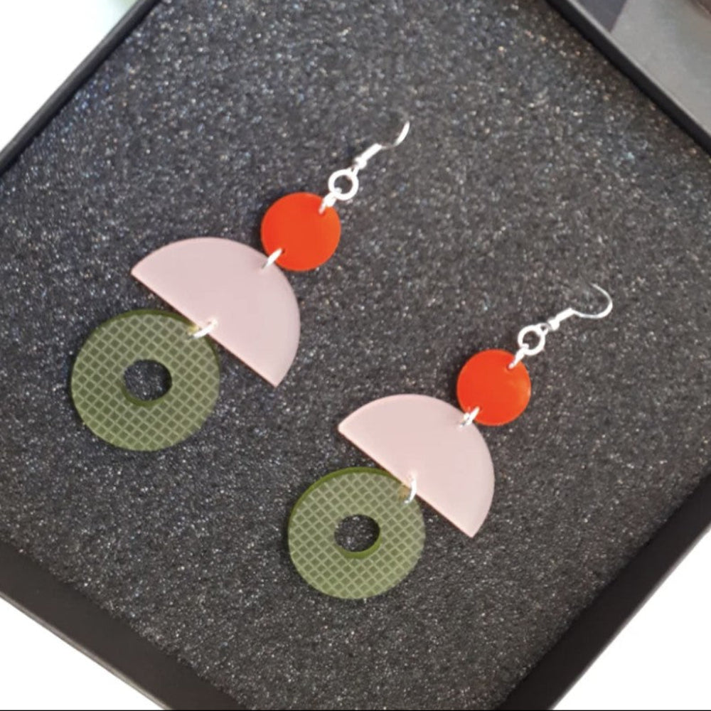 Colorful geometric earrings on a textured black surface