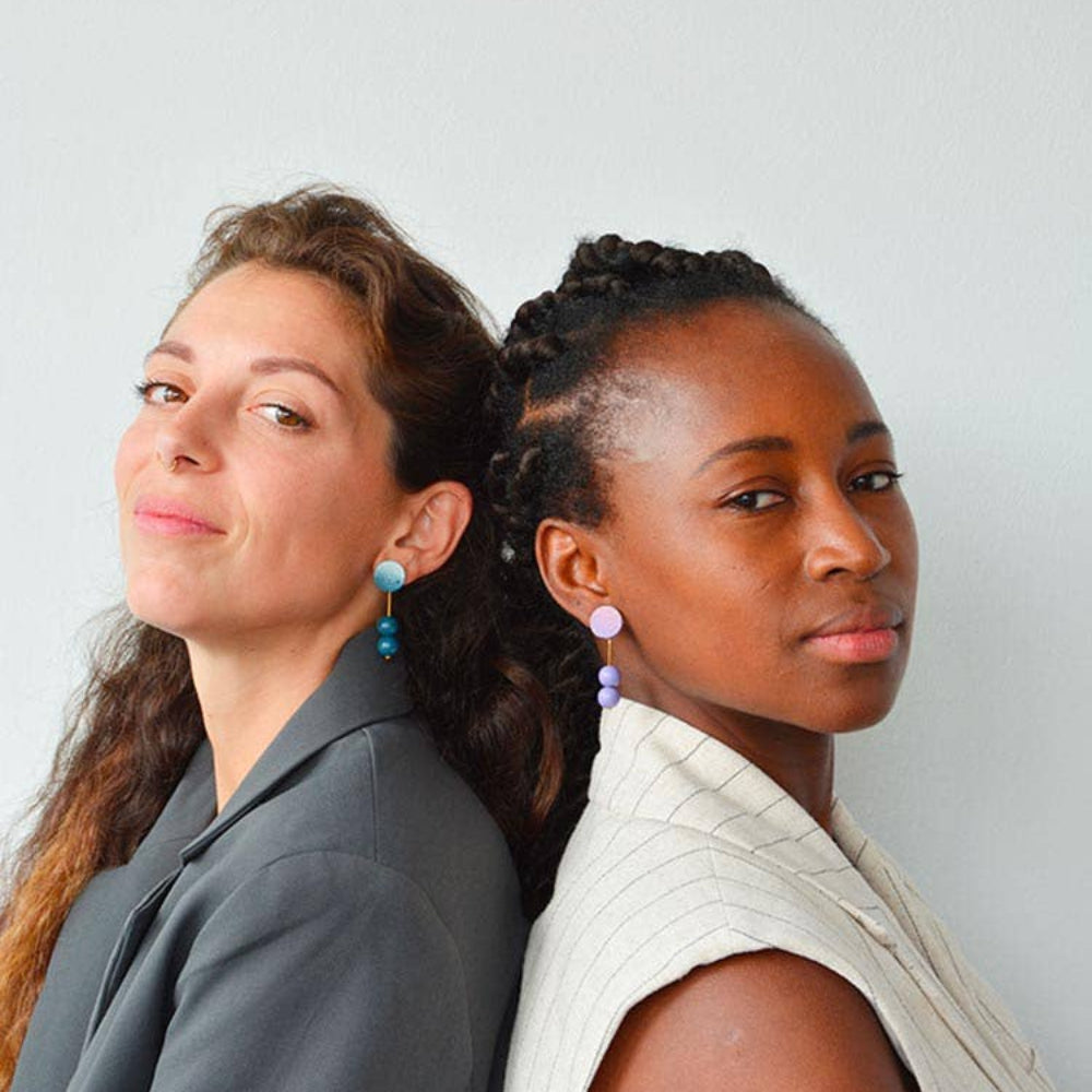 Two women standing back-to-back against a plain background