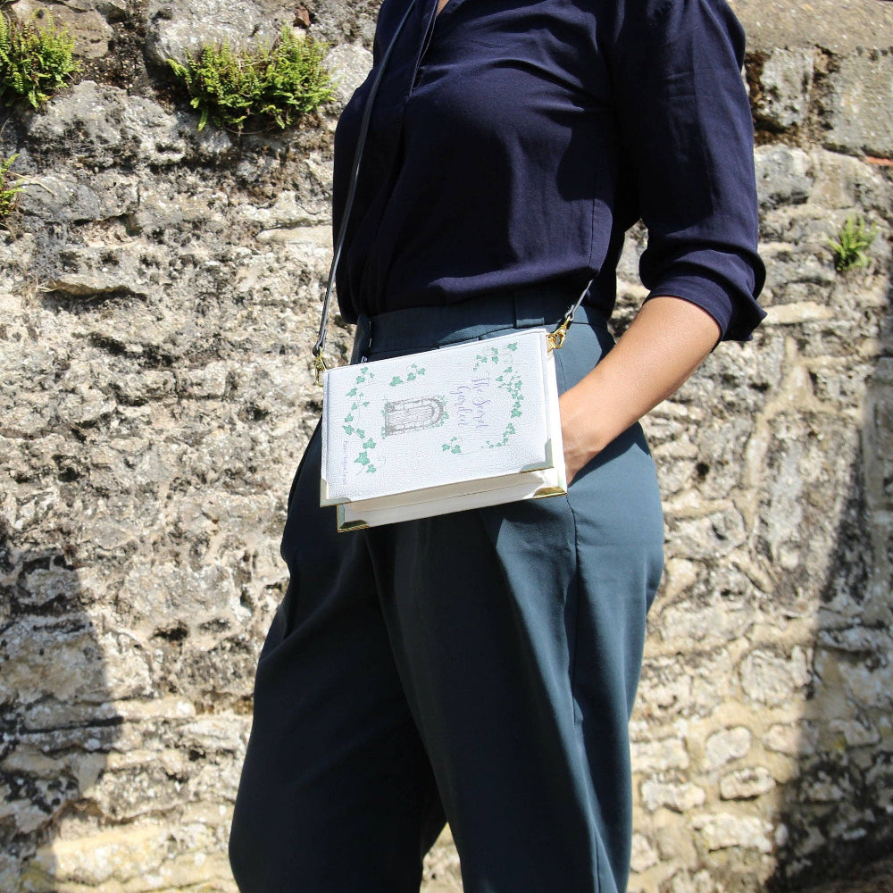 Person holding a patterned bag against a stone wall