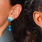 Close-up of two people wearing colorful earrings with a blurred background.