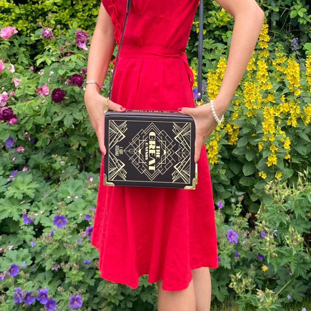 Person in a red dress holding a black clutch with gold design against a floral background