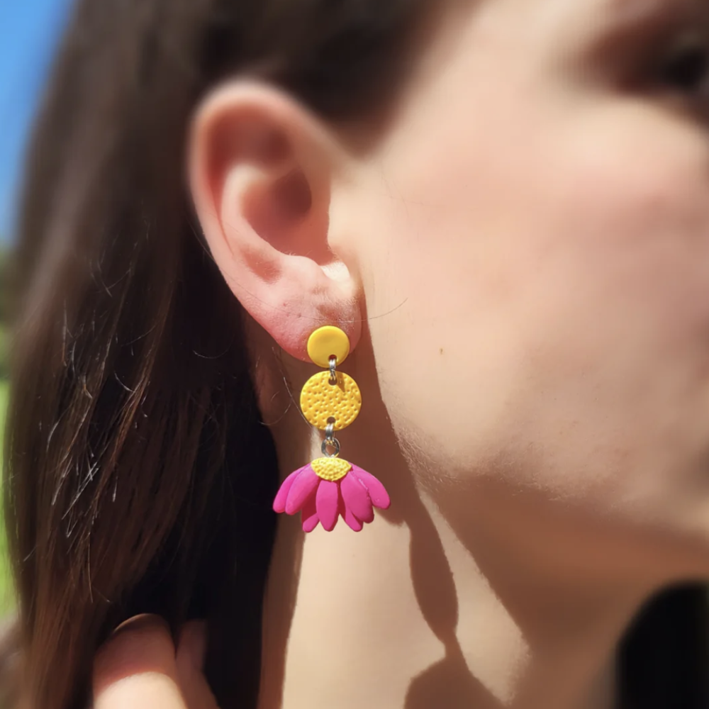 Close-up of a person wearing colorful earrings with a blurred background