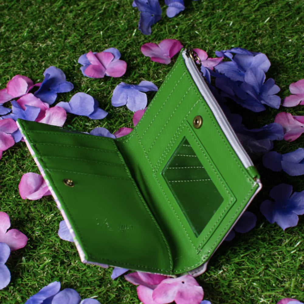 Green wallet on grass with pink and purple flowers