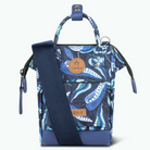 A small top-handle crossbody bag with a blue and white paisley pattern, featuring a solid navy blue shoulder strap, a front zip pocket, and tan leather brand patches reading 'CABAIA' on a white background.