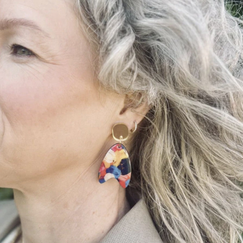 Close-up of a woman wearing colorful earrings with a blurred natural background