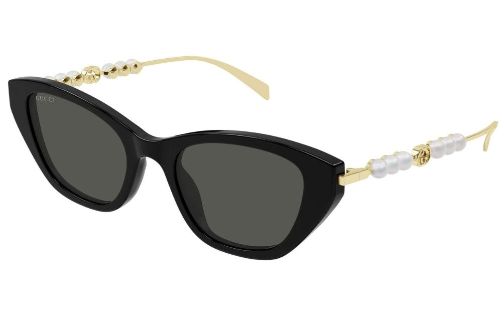Black cat-eye sunglasses with gold and pearl-studded arms on a white background