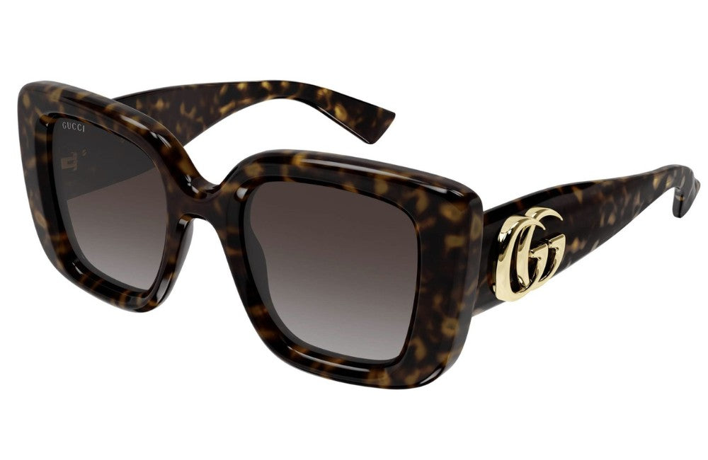 Sunglasses with tortoiseshell frame and gold Gucci logo on a white background