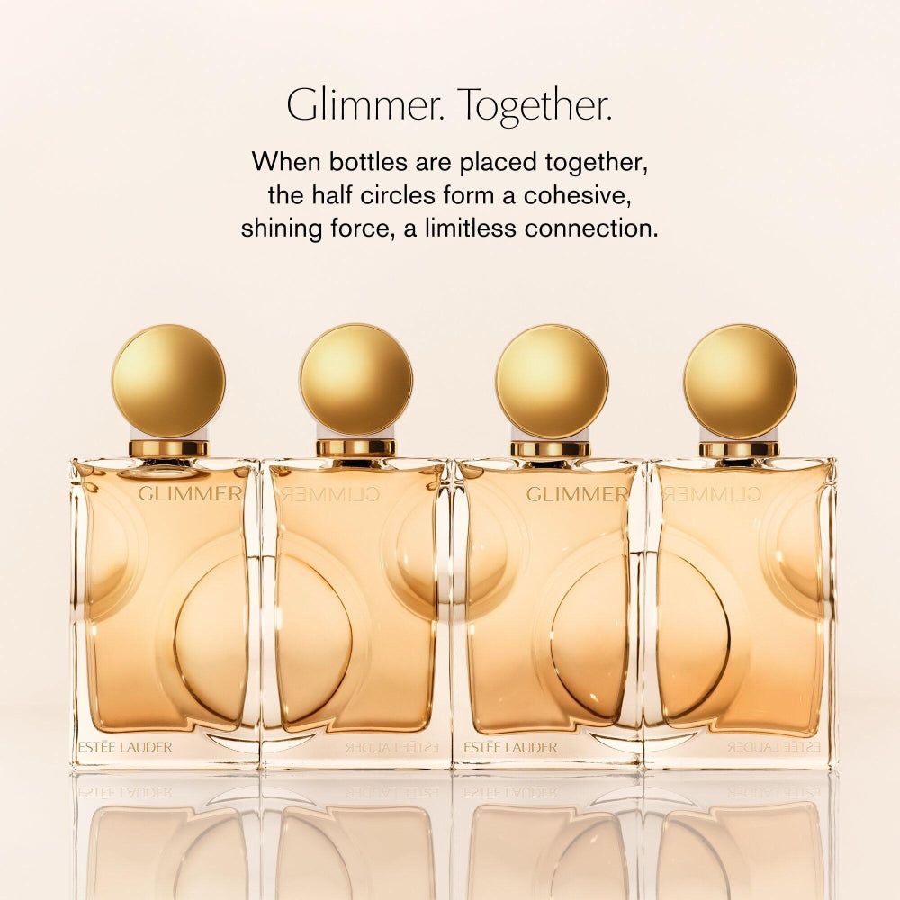 Four Estée Lauder Glimmer perfume bottles arranged together on a light beige background with promotional text above.