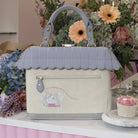 Handbag with scalloped top handle and floral arrangement in the background