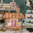 Decorative handbag designed like a small store with books and travel items in the background