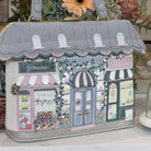 Handbag designed like a quaint town street with shop fronts, featuring a gray roof and colorful storefronts.