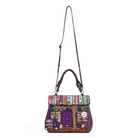 A purple handbag designed to look like a whimsical bookshop, featuring colorful book spines along the top, a purple door, and a tree motif, with a long shoulder strap, shown on a plain white background.