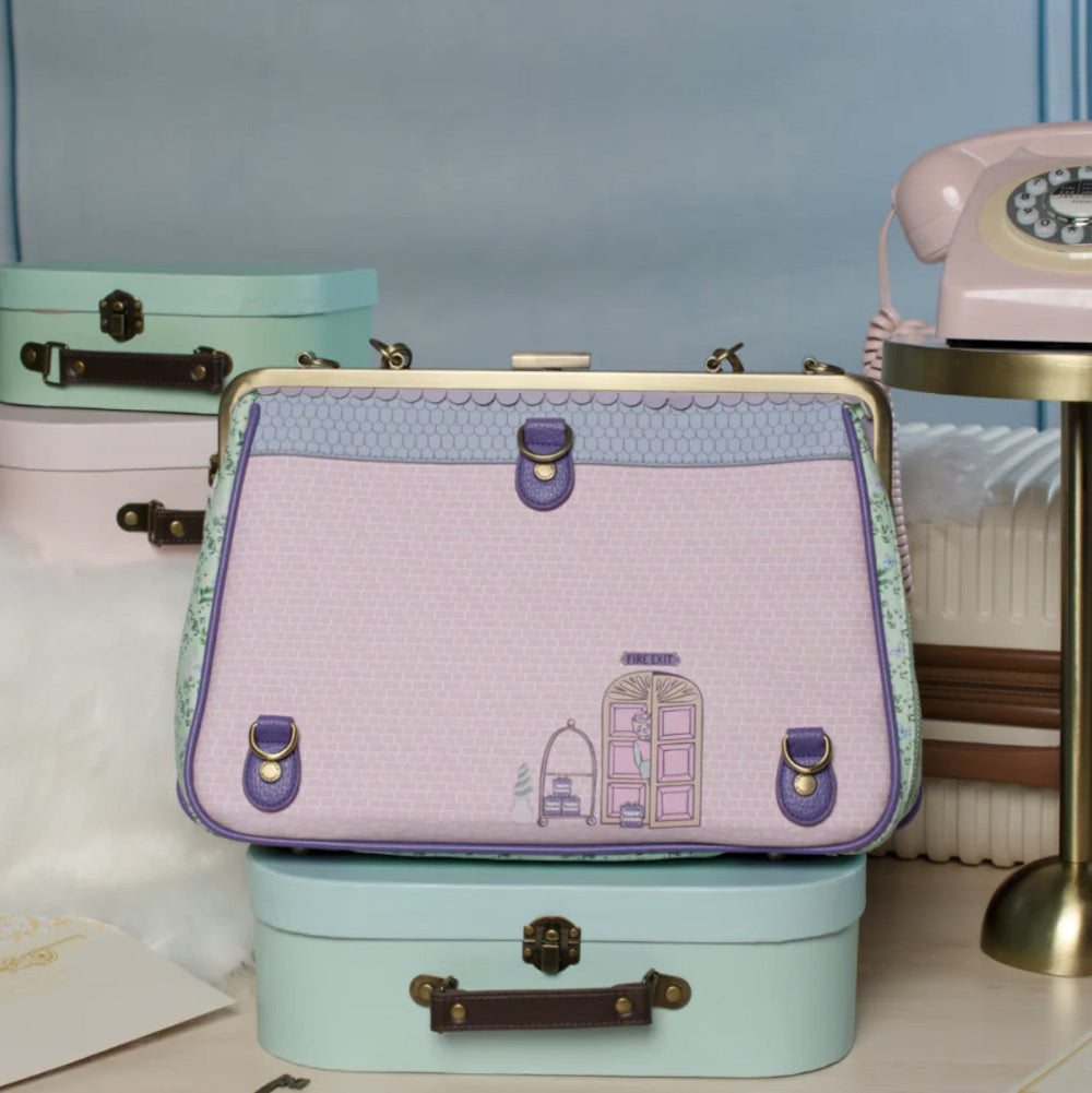 Vintage-style handbag with embroidery on a stack of small suitcases with a blue background.