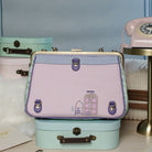 Vintage-style handbag with embroidery on a stack of small suitcases with a blue background.