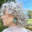 Woman with gray hair wearing green earrings outdoors