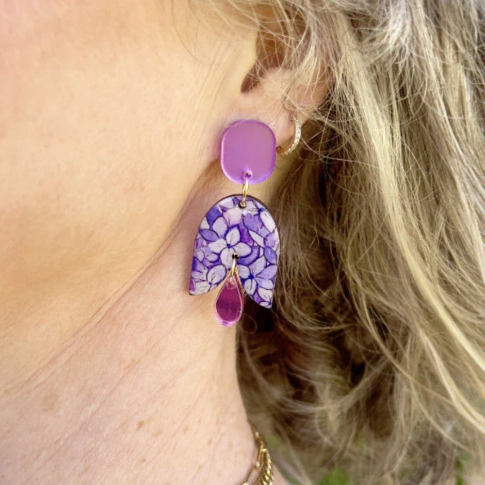Close-up of a person wearing a purple floral earring.