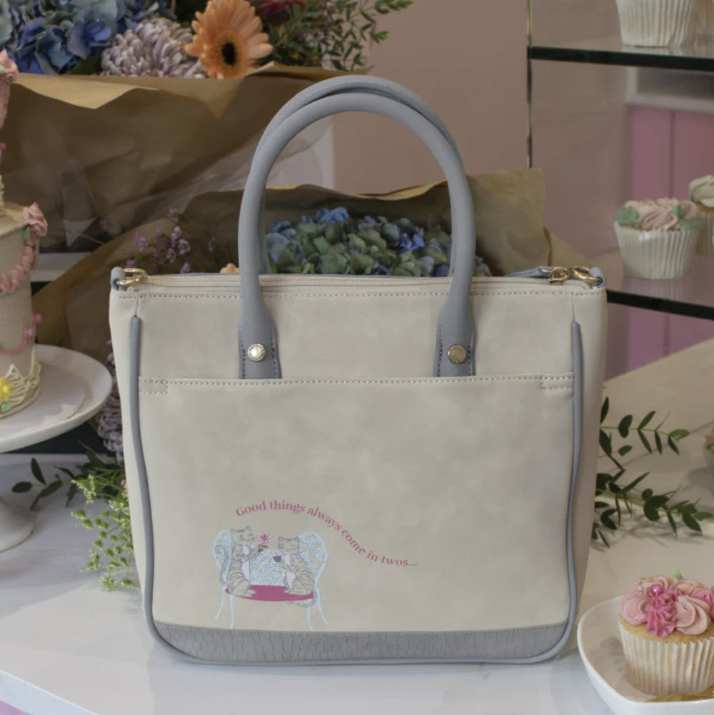 Beige handbag with gray handles on a table with decorative items