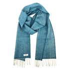 A blue herringbone woven scarf with cream fringe ends and a small white brand label, displayed on a clean white background.