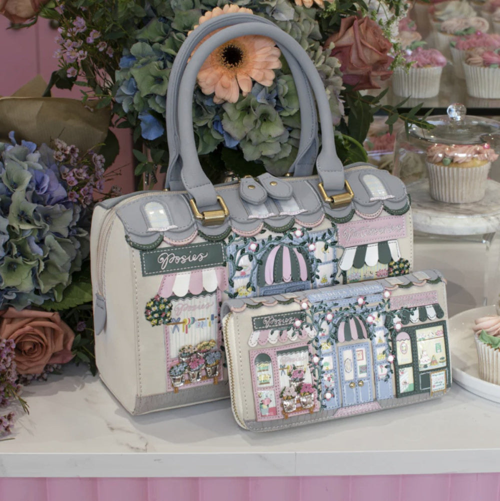 Decorative handbag with shop design on a table with flowers and cupcakes in the background
