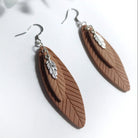 Brown feather-shaped earrings with silver details on a white background