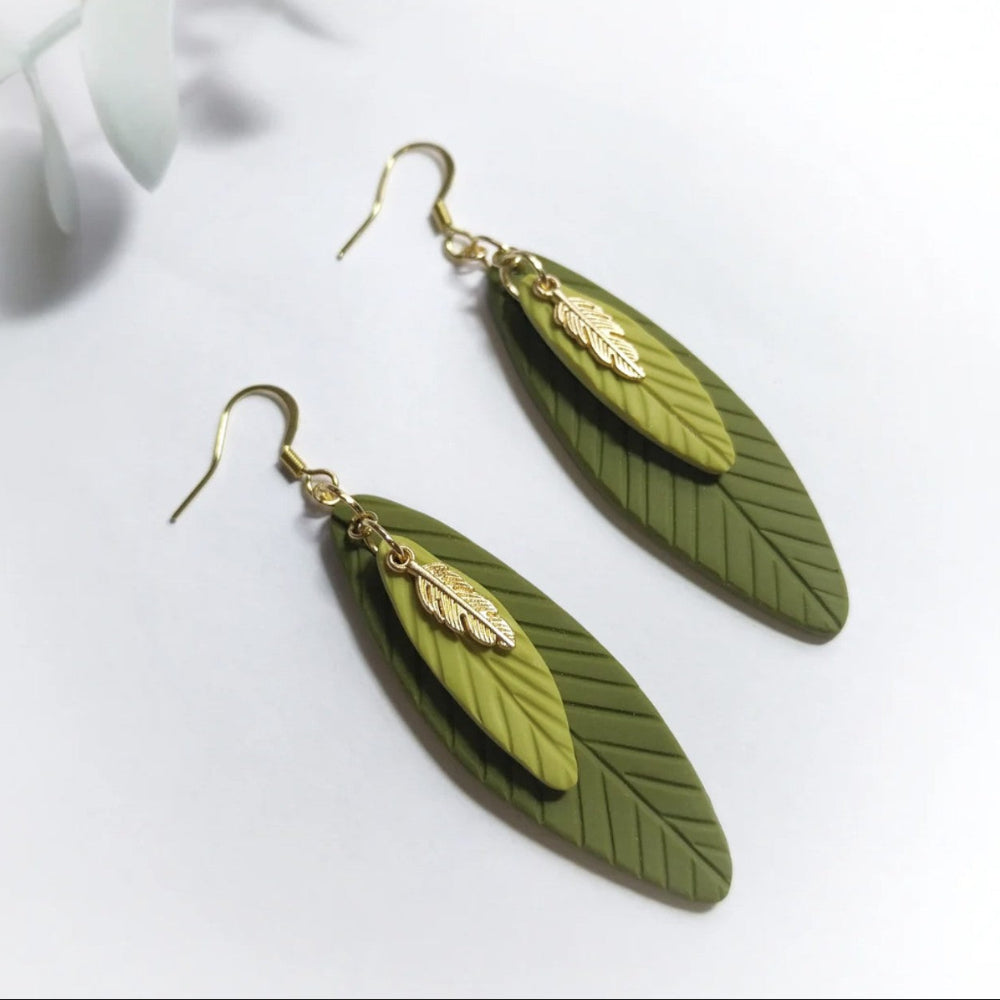 Green leaf-shaped earrings with gold accents on a white background