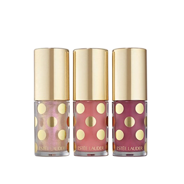 Three Estée Lauder nail polishes with gold caps on a light gray background