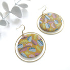 Pair of round earrings with colorful leaf pattern on a white background