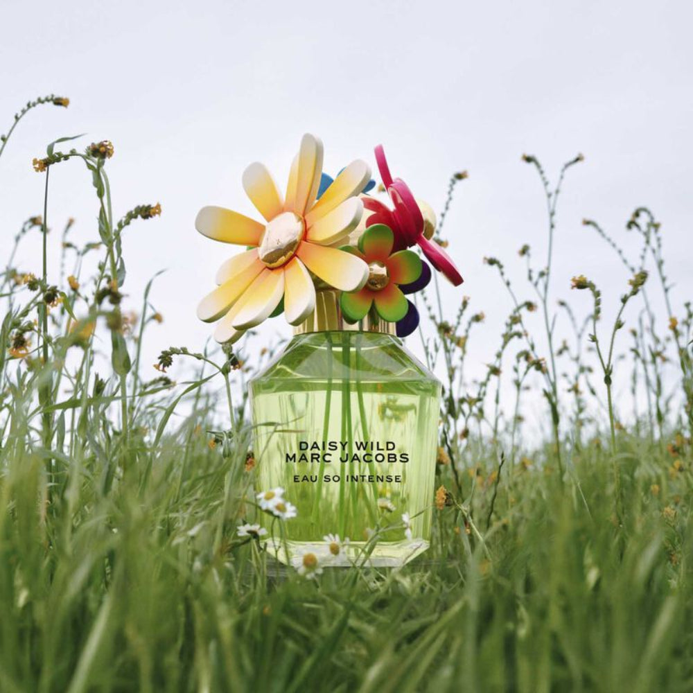 Marc Jacobs Daisy Wild perfume bottle with colorful flowers on top in a grassy field