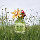 Marc Jacobs Daisy Wild perfume bottle with colorful flowers on top in a grassy field