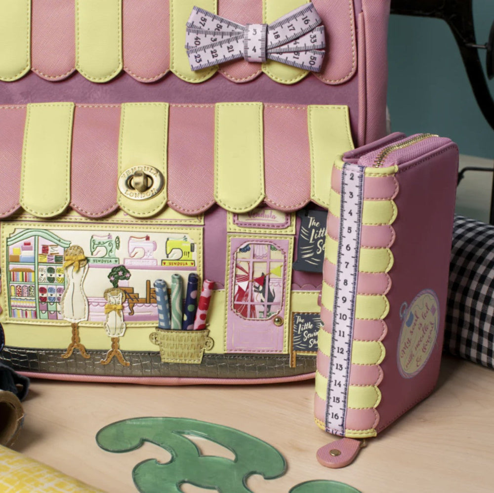 Pink and yellow sewing-themed wallet with a bow and measuring tape detail.