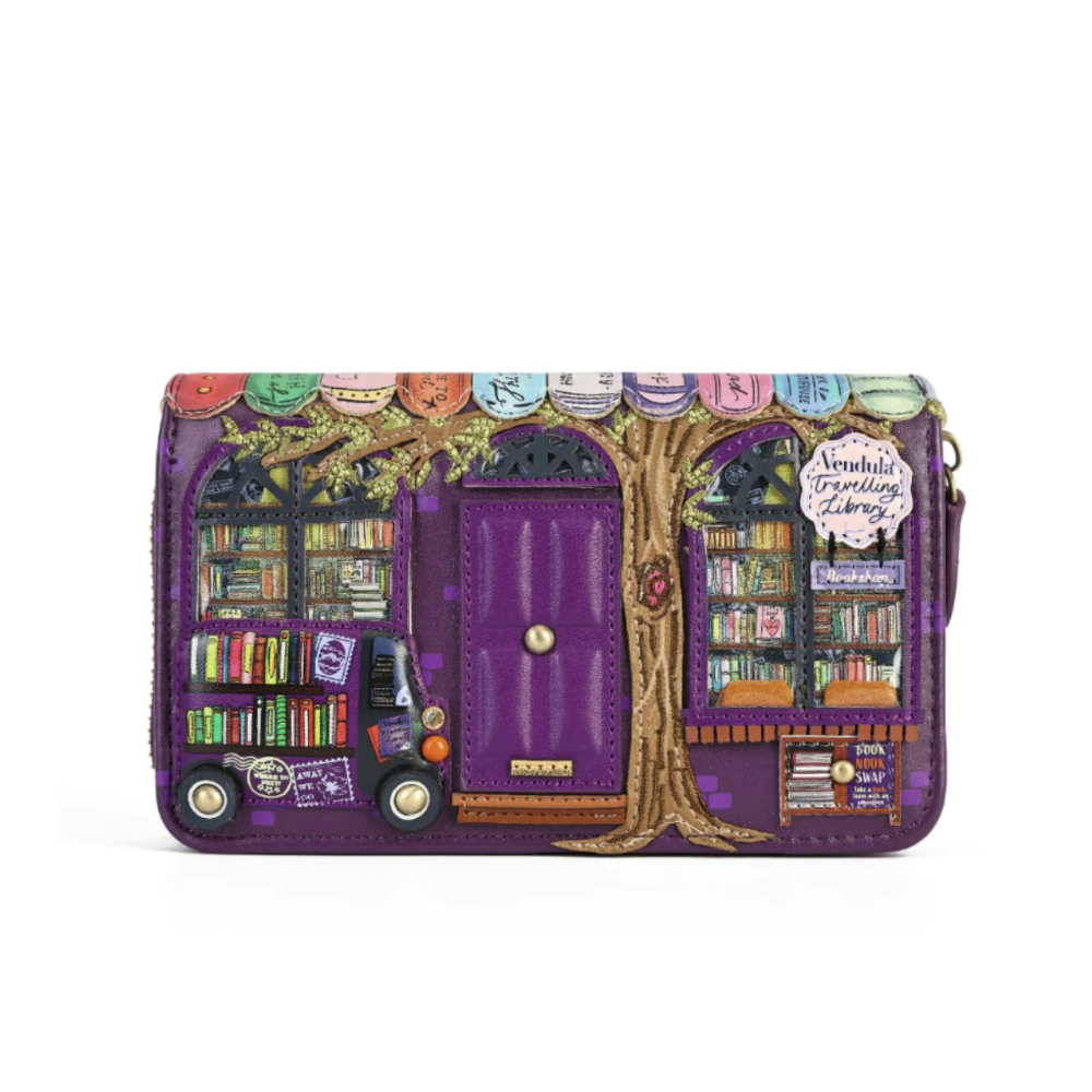 A purple zip-around wallet featuring a whimsical library-themed illustration with a purple door, bookshelves, a tree, a book truck, and a sign reading 'Vendula Travelling Library'.