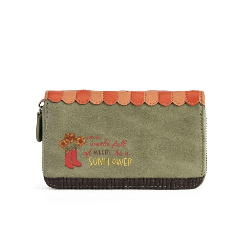 An olive green zip-around wallet with a scalloped orange-brown leather top trim, a dark brown stitched bottom edge, and embroidered red boots, sunflowers, and the phrase 'in a world full of weeds be a SUNFLOWER' on the front.