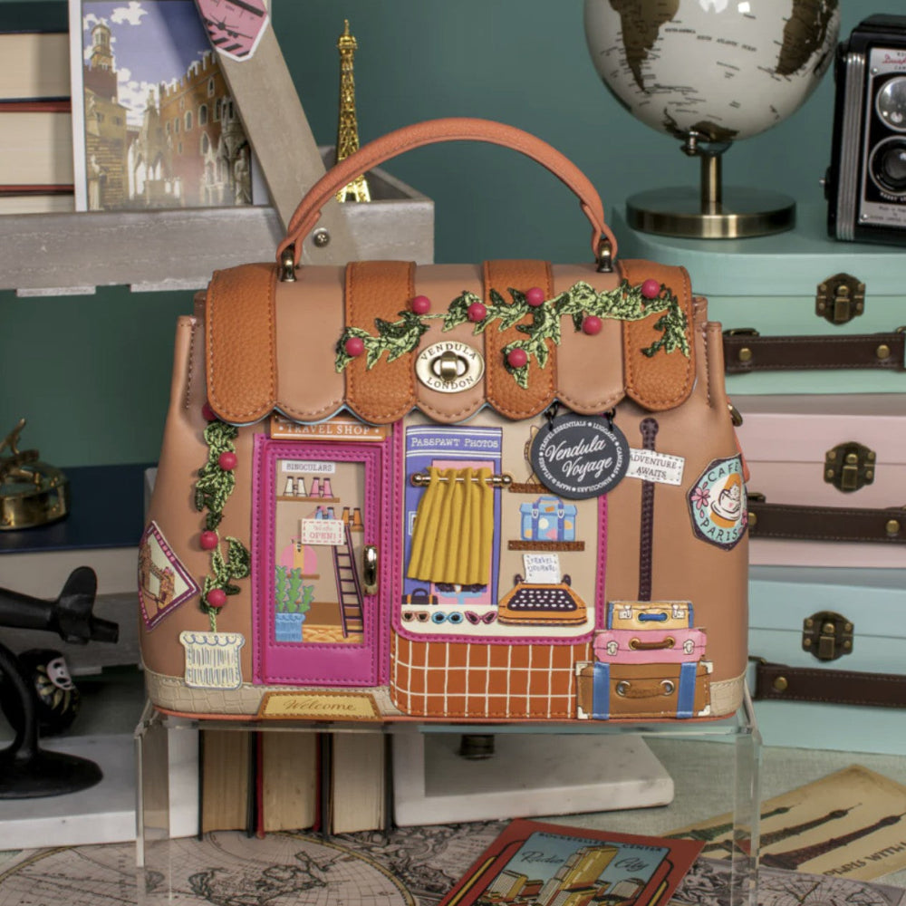 Decorative handbag with embroidered scenes on a glass table
