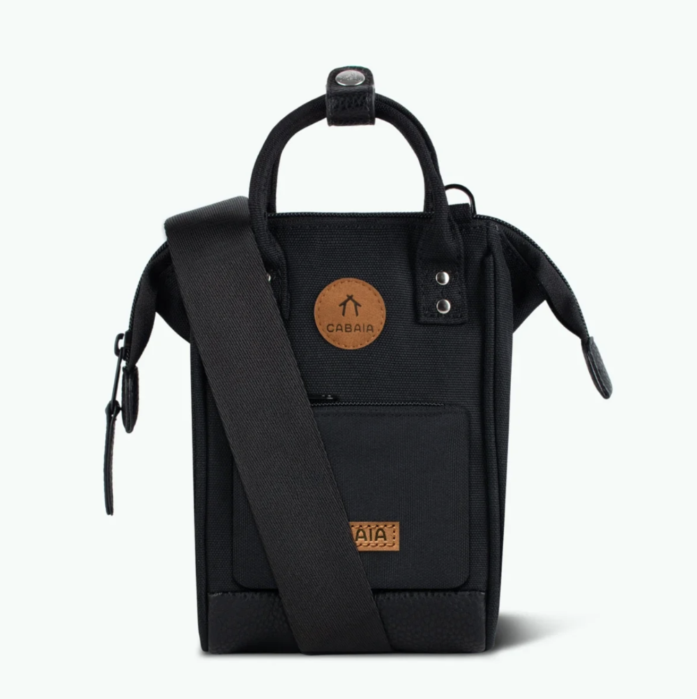 A black Cabaia shoulder bag with a top handle, adjustable shoulder strap, and two circular brown leather brand patches, shown against a plain white background.